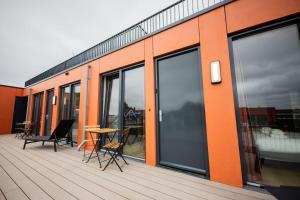 鹿特丹Exquisite 3 Bedroom Apartment的一座橙色的建筑,甲板上摆放着桌椅