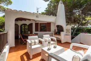 卡拉莫若尔Villa Menorca Ses Roques Vermelles by Mauter Villas的庭院设有白色椅子和壁炉