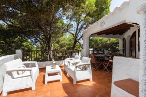 卡拉莫若尔Villa Menorca Ses Roques Vermelles by Mauter Villas的庭院配有白色的椅子和桌子,树木繁茂