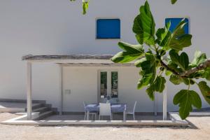 马丁纳弗兰卡Casa Vacanze Villa Greca的海滩上带桌椅的房子