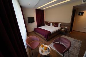 普里兹伦Monarch Hotel的酒店客房带一张床、一张桌子和椅子
