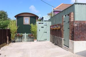 文特诺Little Worsley and The Shepherds Hut的绿色的房子,有门和栅栏