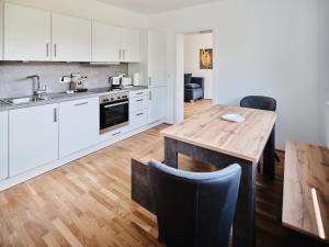 维也纳MySchönbrunn Apartments的厨房配有白色橱柜和木桌
