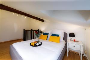 利布尔讷- Le P'tit nid -的一间卧室配有白色的床和黄色及蓝色枕头