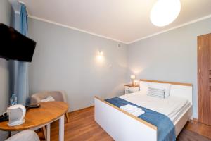 MinikowoHotel Rozmaryn i Lawenda的一间卧室配有一张床、一张桌子和一台电视。