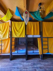 马尔特维利Cha Cha Backpackers的配有黄色和蓝色窗帘的宿舍间内的一张双层床