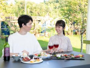 NomaBAMBOO RESORT MIHAMA TSUNAGI - Vacation STAY 43081v的坐在餐桌旁吃酒的男人和女人