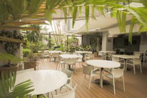 巴拿马城黎明之塔酒店及套房的一间设有白色桌椅的餐厅,种植了植物