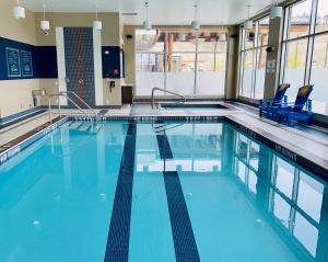 基洛纳基洛纳机场福朋喜来登酒店的大楼内带蓝色椅子的大型游泳池