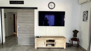 圣吉尔莱班Villa HIMANI的一间设有木桌的墙上电视的房间