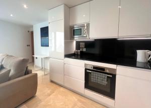 直布罗陀Luxury 1 Bed - City Suites Ocean Spa Plaza的厨房配有白色橱柜和微波炉