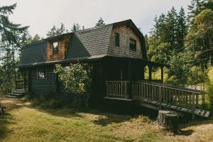 FernwoodBodega Ridge & Cove Cabins的一座大型的黑色房子,在院子里设有门廊