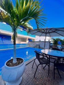 里约达欧特拉斯马雷西亚科斯塔阿苏尔旅馆的坐在桌子旁的棕榈树,带雨伞