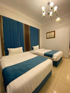 阿哈达منتجع أرين للوحدات السكنية的两张位于酒店客房的床,配有蓝色窗帘