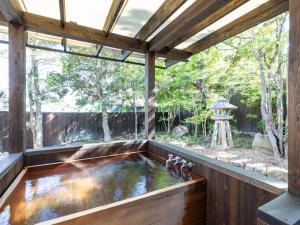 白滨Tabist Nanki Shirahama Ryokan Mantei的木质房屋内的室内锦 ⁇ 池塘,设有大窗户