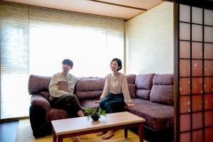 热海Yuyado Ichibanchi的坐在沙发上的男人和女人