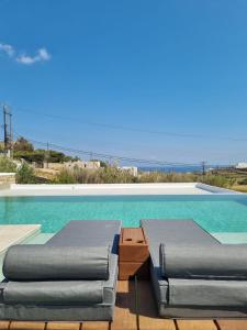 米克诺斯城Abelos Mykonos的游泳池旁设有2把躺椅和躺椅