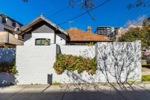 悉尼Crows Nest LemonTree Cozy 3 Bedroom House的白色砖墙,上面有植物
