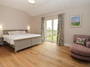 奇平诺顿Cotswold View的一间卧室设有一张床、一个窗口和一把椅子