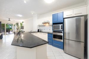 凯恩斯Cairns Esplanade 2BR Waterfront Apartment Sleeps 6的厨房配有蓝色橱柜和不锈钢冰箱