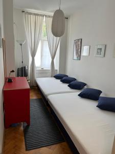 克拉科夫克拉科夫西维奥公寓式酒店的配有红色桌子和窗户的客房内的三张床