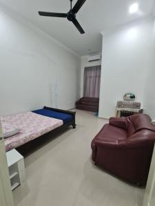 甘榜甘马挽OLIA MEDINA KERTEH 4 BILIK HOMESTaY的一间卧室配有一张床和一张沙发