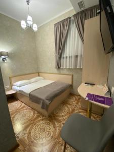 基辅Grand Christer Hotel的一间卧室配有一张床、一张桌子和一把椅子
