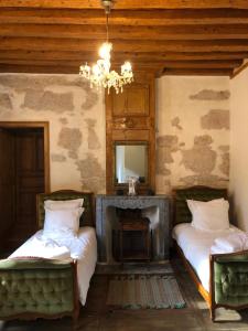MontangesDomaine du Très-Haut - Château de Montanges的客房设有两张床、镜子和吊灯。