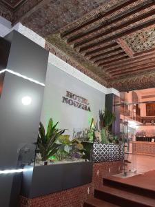 非斯Hotel Nouzha的大堂设有酒店的新星标志和植物