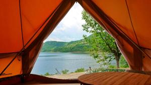 Staro MyastoLakeview Glamping的橙色的帐篷享有湖景