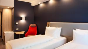 波鸿Holiday Inn Express Bochum, an IHG Hotel的酒店客房,设有两张床和一张红色椅子