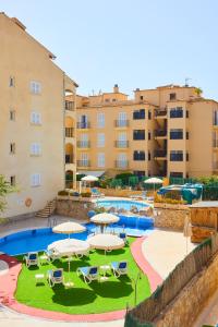 卡拉博纳Sol y Mar Apartments的一个带遮阳伞和椅子的游泳池以及建筑