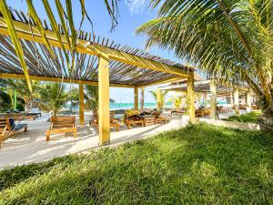 帕杰Jambo Beach Hotel Paje的一个带木桌和椅子的庭院和大海