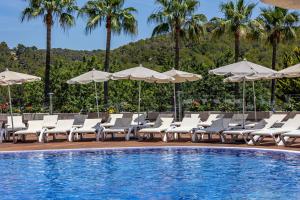 帕格拉Ona Palmira Paradise的游泳池旁设有白色躺椅和遮阳伞的游泳池