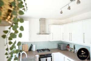 沃灵顿Bee Stays - Ambleside House的厨房配有白色橱柜和炉灶烤箱。