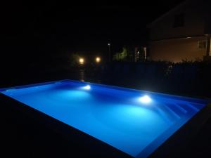 皮内兹齐Lavanda Apartments&Studios的游泳池在晚上点亮,灯光蓝色