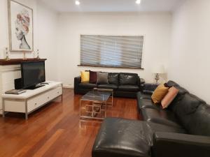 弗里曼特Leisurely Manor - spacious three bedroom home in Fremantle的客厅配有黑色真皮沙发和电视