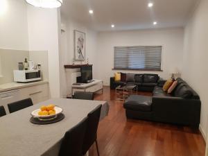 弗里曼特Leisurely Manor - spacious three bedroom home in Fremantle的客厅配有黑色沙发和桌子