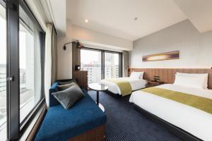 川崎HOTEL METROPOLITAN KAWASAKI的酒店客房设有两张床和窗户。