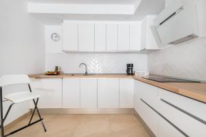 阿里纳加Casa Daura Playa de Arinaga 2023 Reformed的厨房配有白色橱柜、水槽和椅子