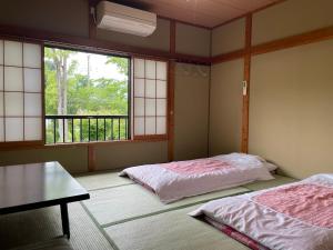 富士河口湖托加瓦索酒店的客房设有两张床、一张桌子和窗户。