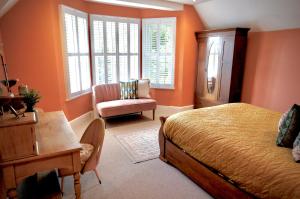 SwayHazelhurst Farm的一间卧室拥有橙色的墙壁,配有一张床和椅子