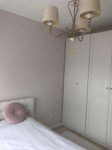 什切青Zaciszny dom的卧室配有白色橱柜和床上的粉红色枕头