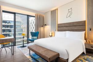 迪拜voco Dubai The Palm, an IHG Hotel的卧室配有白色的床、书桌和椅子