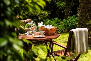 蓬塔德尔加达Azores Green Villas的坐在桌子旁的女人,拿着一篮子的葡萄酒