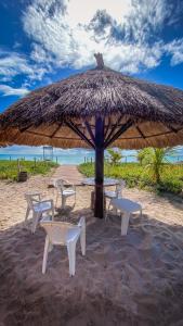 马拉戈日Village Miramar的海滩上草伞下的桌椅