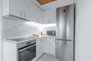 库鲁塔KOUROUTA BEACH HOUSE的厨房配有白色橱柜和不锈钢冰箱