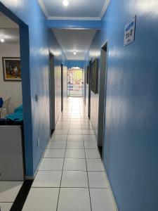 卡马穆Pousada o Paraiso的走廊设有蓝色的墙壁和白色的瓷砖地板