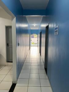 卡马穆Pousada o Paraiso的走廊设有蓝色的墙壁和瓷砖地板