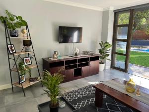 比勒陀利亚Afrique134 Baobab Tree Private Family Garden Suite的客厅配有电视和木桌。